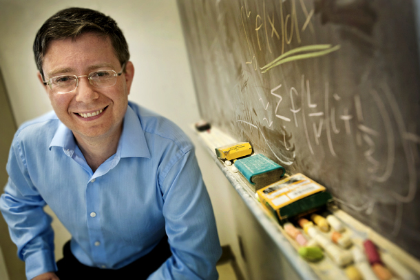 Lev Kaplan poses near a chalkboard