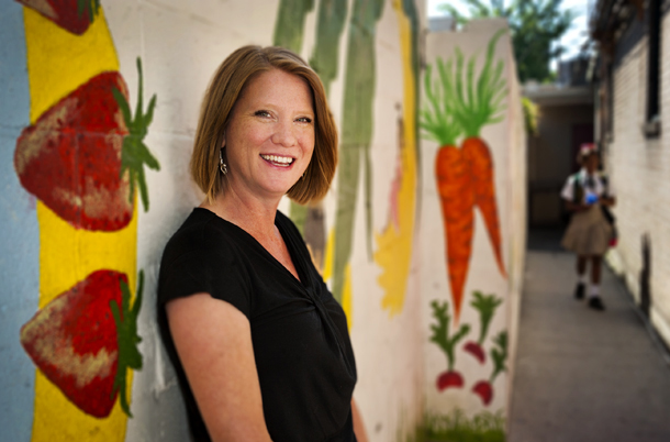 Stacy Overstreet poses in front of a mural depicting fruits and vegetables