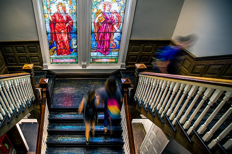 Figures in Tiffany windows keep a watchful eye over the stairs in Tilton Memorial Hall. 