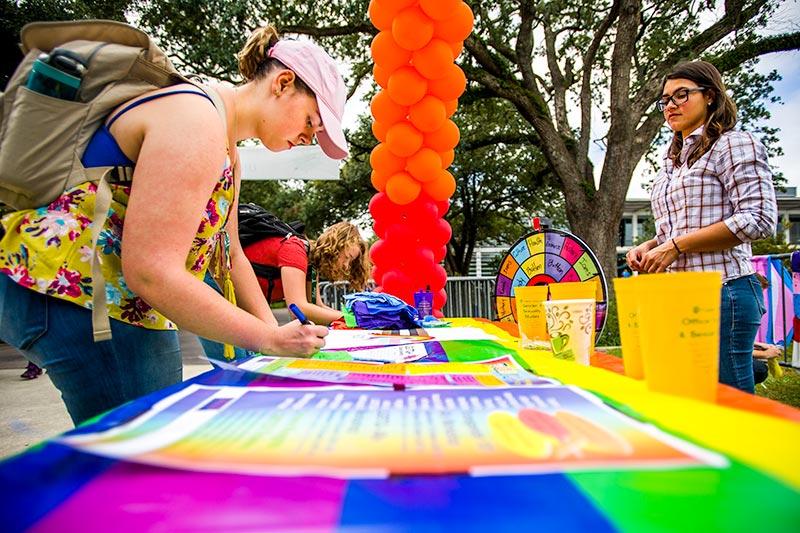 Students decorate a banner with positive messages for the start of Pride Month at Tulane.