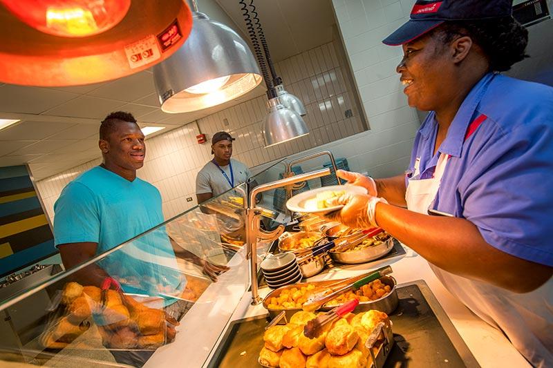 Leslie Young, a member of the Tulane Dining Services staff, greets Green Wave defensive end Robert Kennedy at the buffet line in Bruff Commons. 