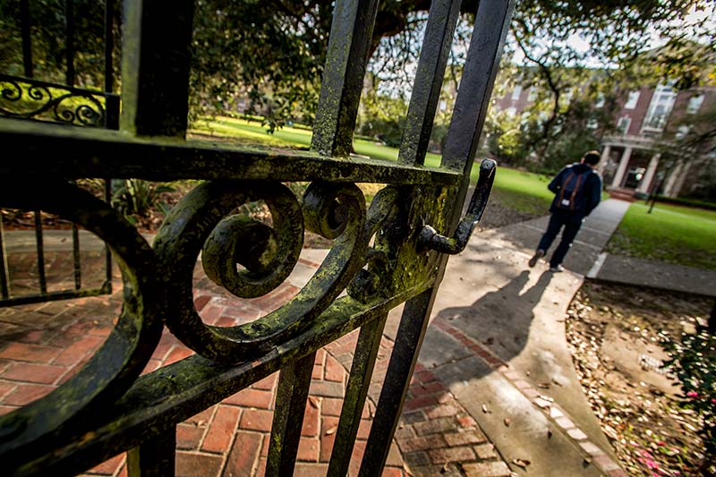 A student passes from Broadway Street through the Newcomb College gate onto the uptown campus