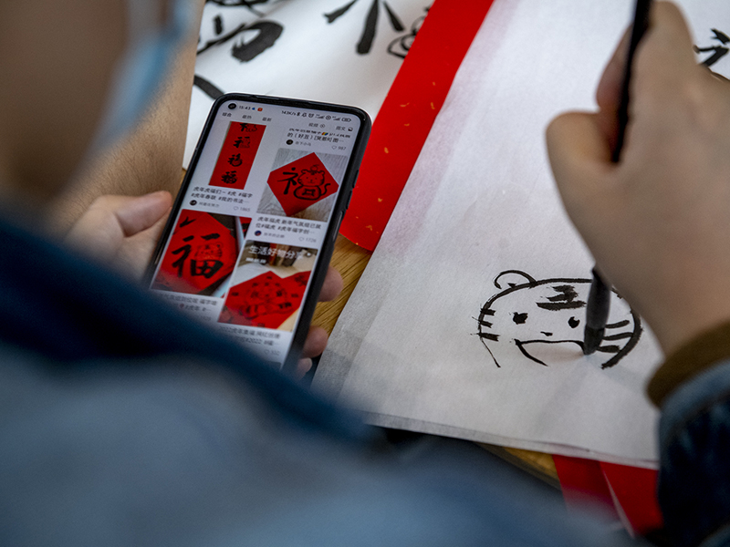 Using a calligraphy brush, a student draws a tiger head. Based on the Chinese zodiac calendar, 2022 is the Year of the Tiger.