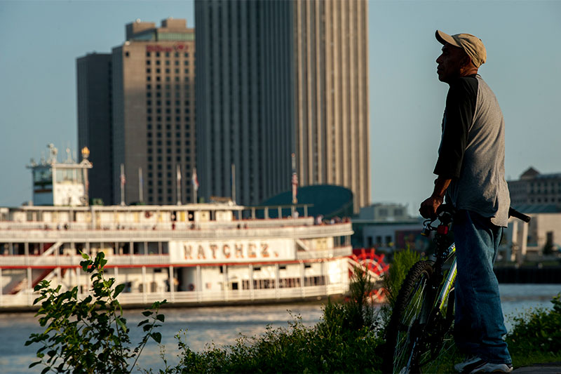 A man pauses on the Moonwalk along the Mississippi River levee near the French Quarter, as the Steamboat Natchez takes off for an evening cruise.