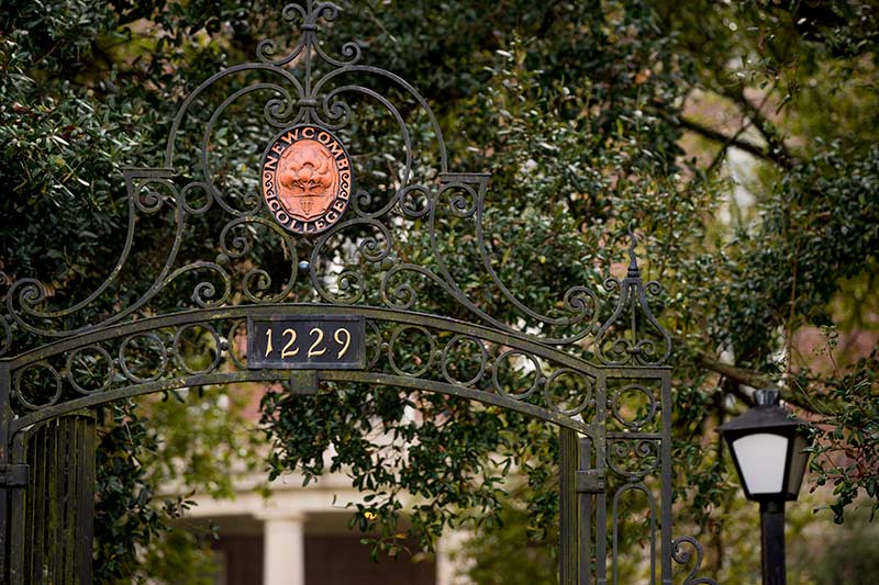 The Newcomb College gate, emblazoned with and surrounded by oak trees, pays homage to the oak grove planted by the founders of the college