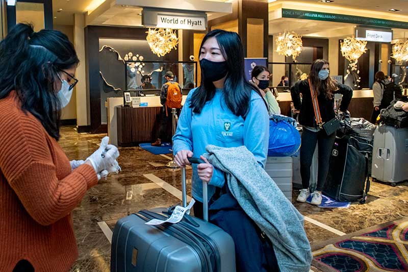 Miccah Izaguirre with the Hyatt Hotel checks Anna Ryu's luggage for the shuttle to campus