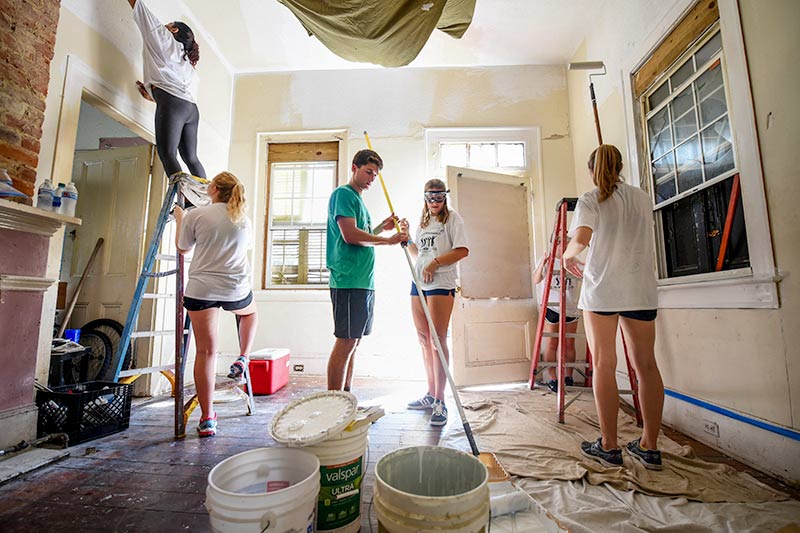 Tulane student Chase Kelly helps Delaney Connor and others paint a living room while volunteering with South Seventh Ward Neighbors.