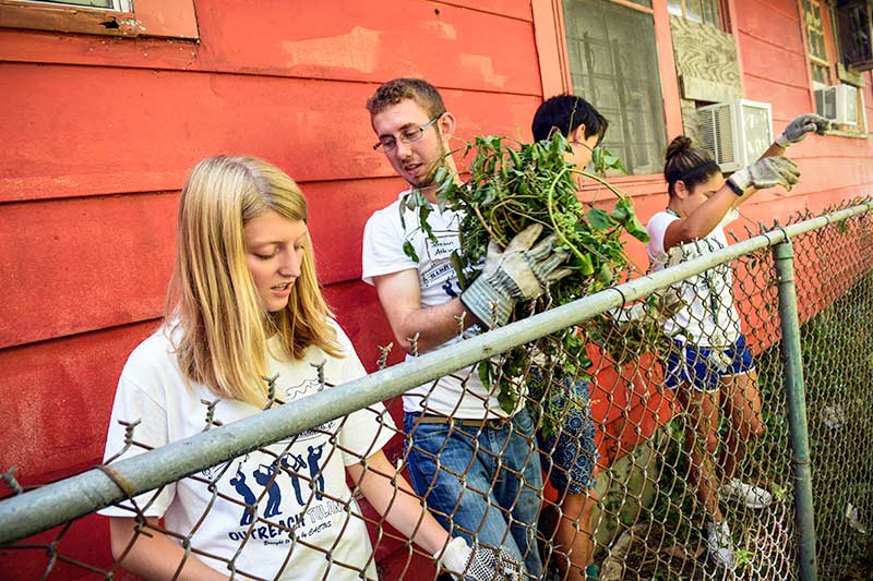 Chase Kelly, center, helps Delaney Connor, second from left, and others paint a living room while volunteering with South Seventh Ward Neighbors.