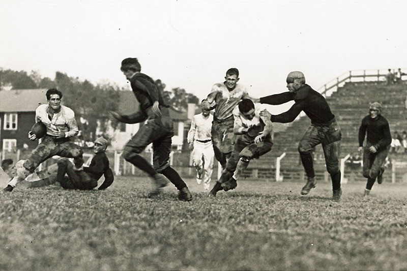 Brother” Brown, captain of the 1924 Green Wave football team, far left, runs the ball as Peggy Flournoy and Gene Bergeret throw blocks on members of the Mississippi College Choctaws