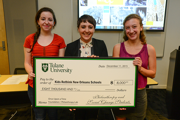 Philanthropy students Jessica Rubini, left, and Abigail Cramer, right, present a grant check to Rachel Lee, center, operations manager of Kids Rethink New Orleans on Friday, Dec. 11. (Photo by Sally Asher)
