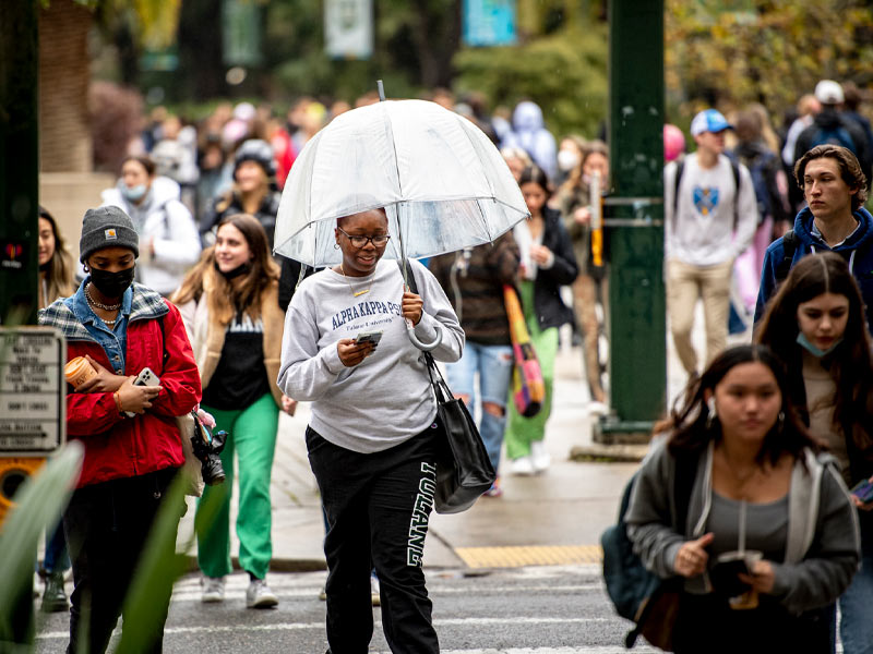 Tulane senior Christiann Cannon, center, shields herself from the rain as she crosses Freret Street on her way to Educational Psyche class on the uptown campus.