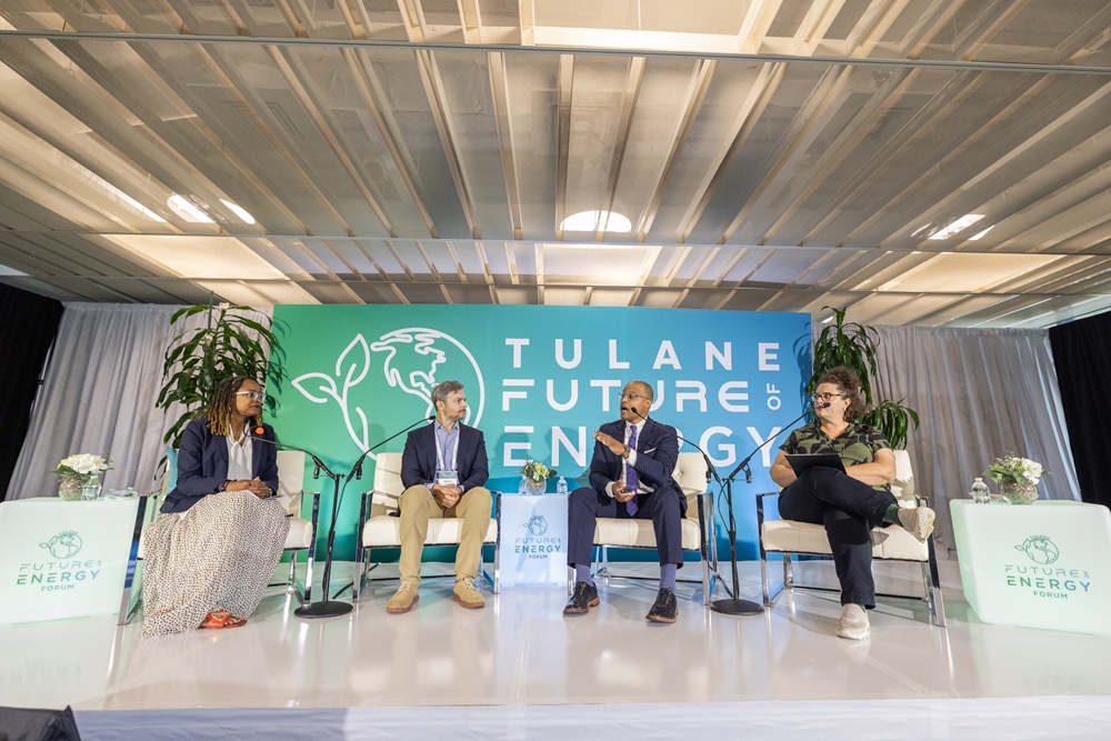 Four people sitting on stage with Tulane Future of Energy backdrop.