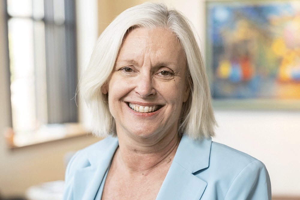 Smiling woman with white hair and a light blue jacket. 
