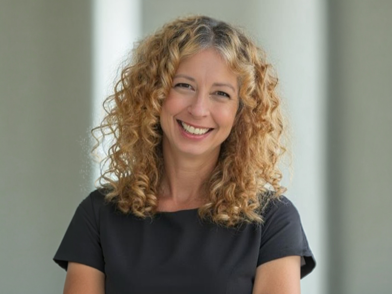 
Headshot of a smiling woman with curly blonde hair. 