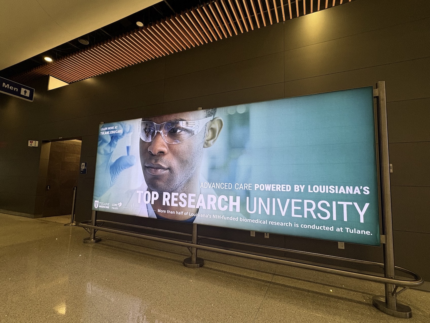 
Large illuminated billboard ad of a man in lab coat, text 'TOP RESEARCH UNIVERSITY'. 