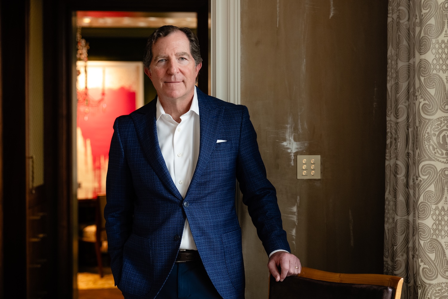 
Professional man in a blue suit and white shirt, standing in a doorway. 