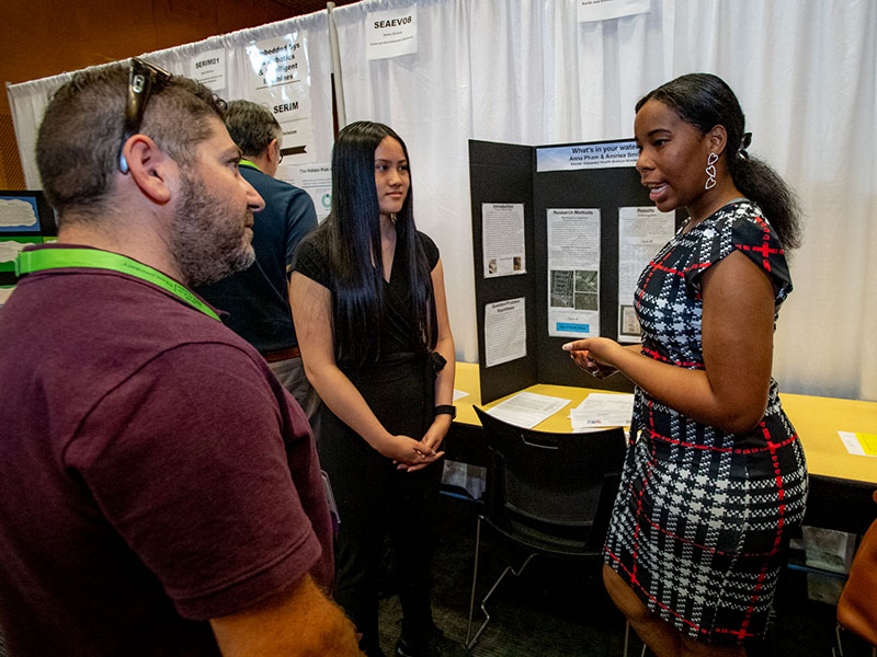Anna Pham, center, and Amiriea Smith share their research on drinking water quality. Both are students at Kenner Discovery Health Science Academy.