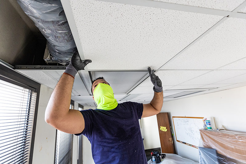 A worker replaces damaged ceiling tiles at School of Public Health and Tropical Medicine’s Tidewater Building.