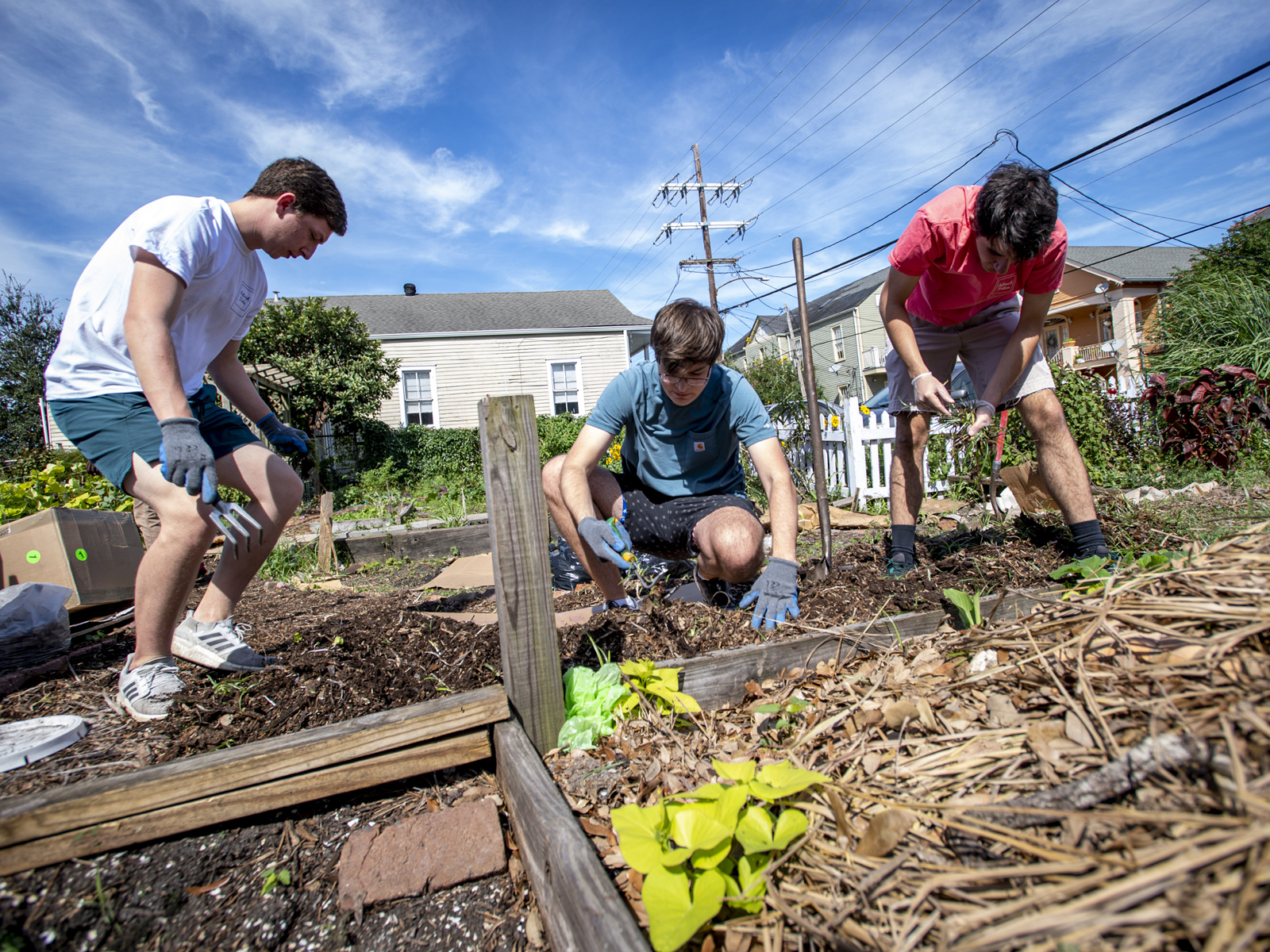 Daniel Marglous, Andrew Terrebonne and John Nuttli, left to right, weed and freshen up a path in the community garden at Hargar’s House NOLA. The garden is filled with herbs for cooking and making medicinal teas.