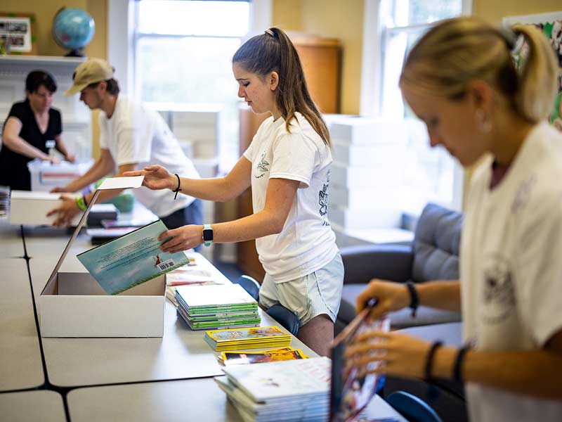 Erin Lindgreen, center, and fellow Tulane University students Nicholas Eclstein, left, and Kat Holtz, right, prepare boxes for reading materials for students participating in the Start the Adventure in Reading (STAIR) program ).