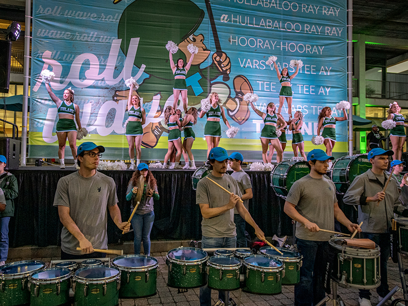 The Tulane University Marching Band plays as the Cheerleading squad performs for the pep rally crowd.