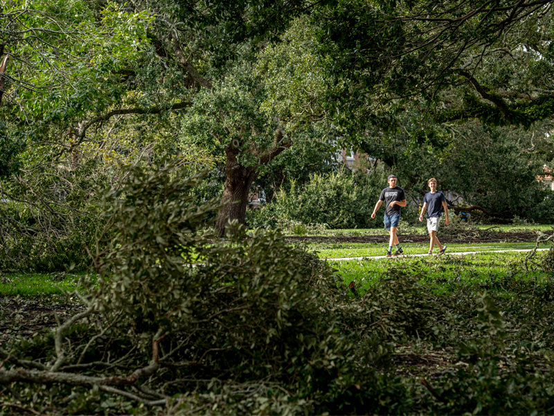 On the uptown campus, students walk past fallen tree limbs following Hurricane Ida. 