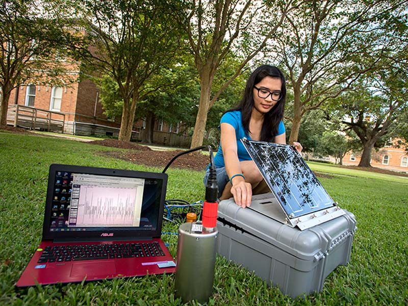 Sarah Oliva, a PhD student in earth and environmental sciences tests a seismometer in the quad near Blessey Hall. The state of the art equipment is headed for New Zealand where it will monitor unusual volcanic earthquakes. The data will help researchers u