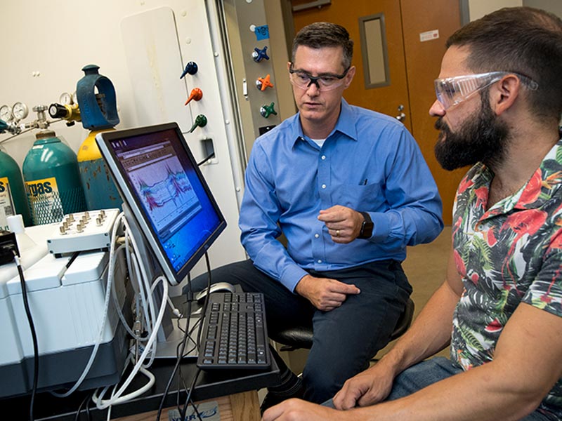 Professor Daniel Shantz (left) and graduate student Ross Ransom analyze data from their research of zeolite SSZ-39 in an effort to reduce harmful chemicals in auto emissions. (photo by Paula Burch-Celentano)