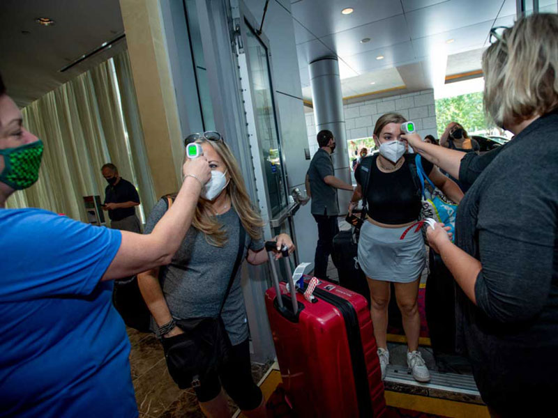 Tulane staff member checks students' temperatures at Arrival Center entrance