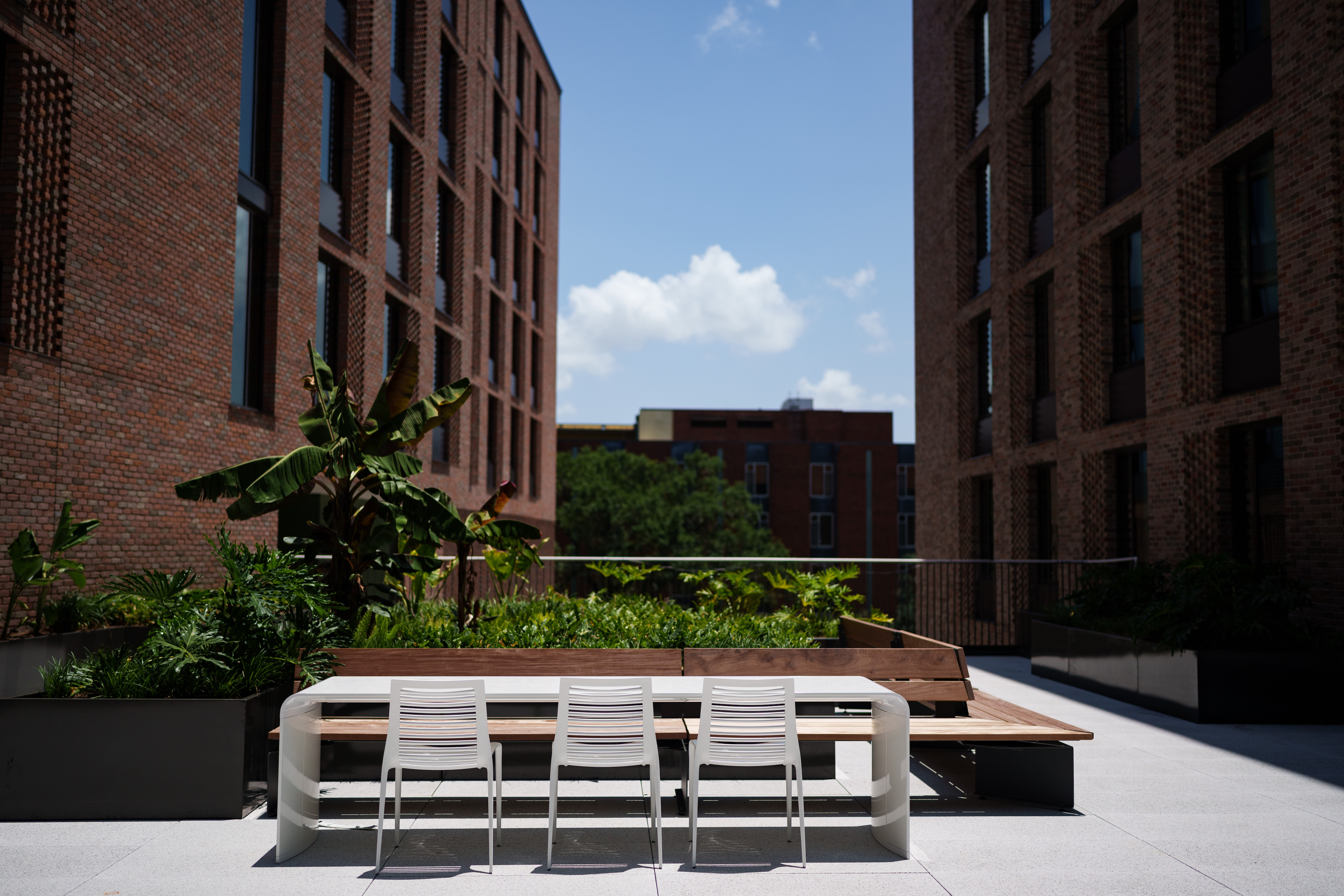 An outdoor courtyard between two looming buildings with greenery and seating
