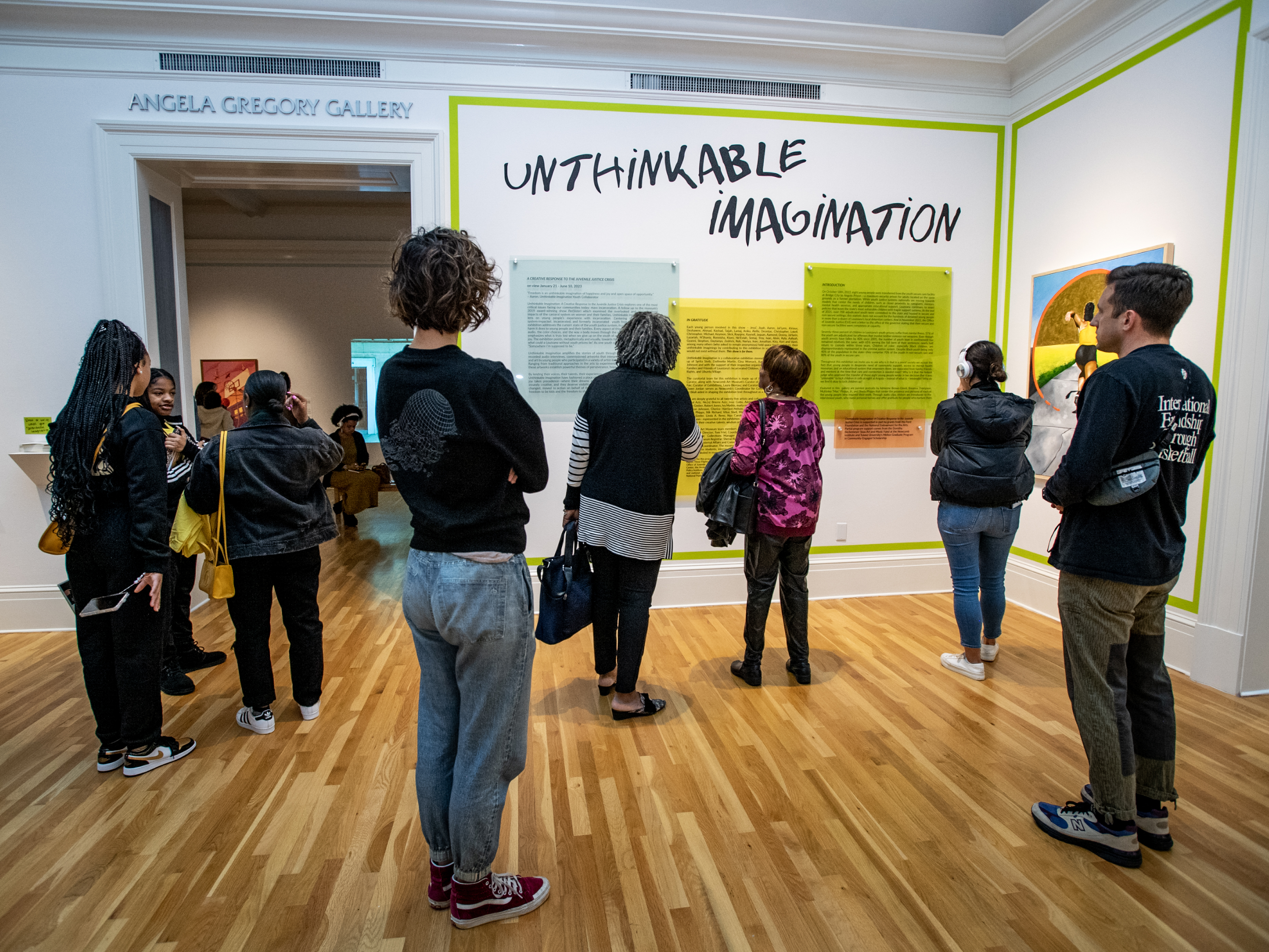 Visitors read the opening statement of the exhibit, which features a range of visual experiments developed in community spaces, through dialogues between artists and youth with direct knowledge of Louisiana’s extensive carceral system.