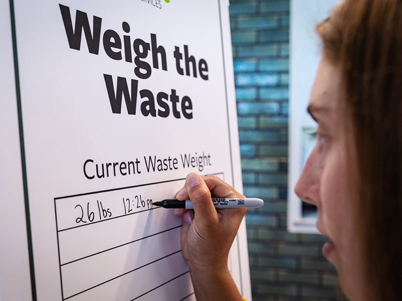 Senior Samantha Mehlman, a student in Professor of Practice Nicole Katin’s Environmental Studies seminar,  writes the weight of the first container weighed during the Weigh the Waste event.