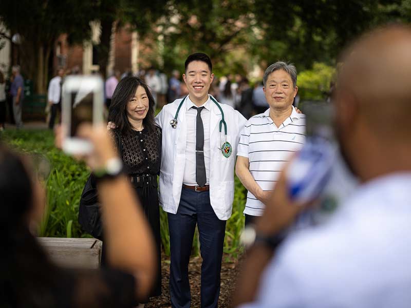 Donning their white coat and stethoscope, a student takes a photo with their family after the ceremony. 