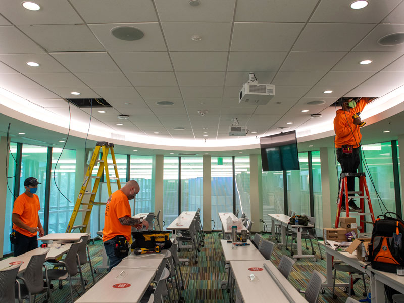 A technology team installs wiring in a classroom in Goldring-Woldenberg Business Complex.