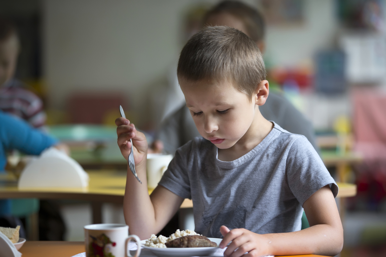 Child looks worryingly at a plate of food 