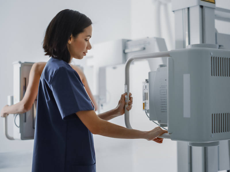 A nurse operates a mammography unit while a patient is scanned.