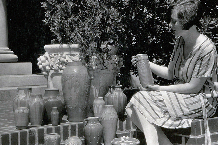 An unidentified woman poses with a collection of Newcomb Pottery. 