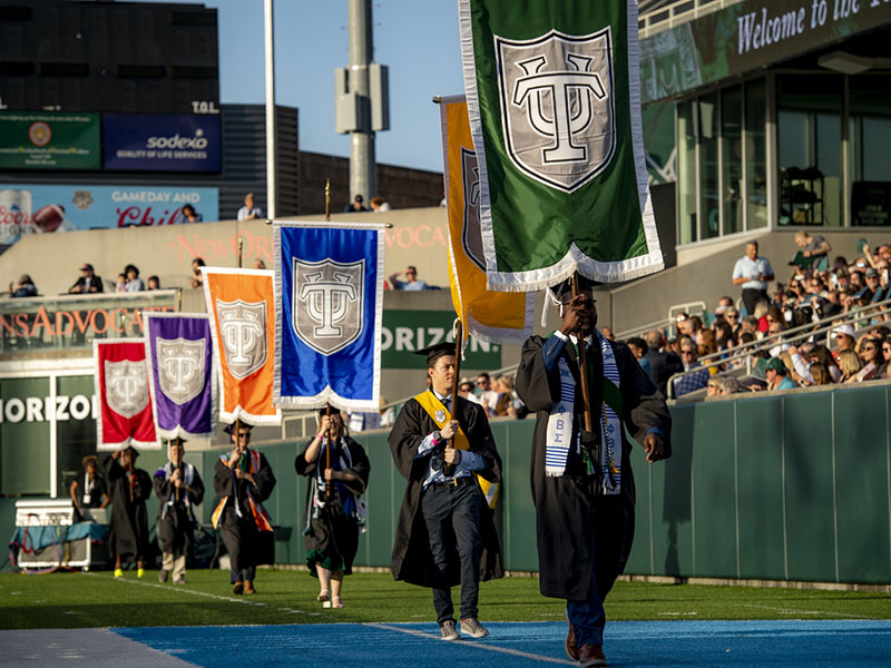 Grads carry flag gauntlets during Commencement.