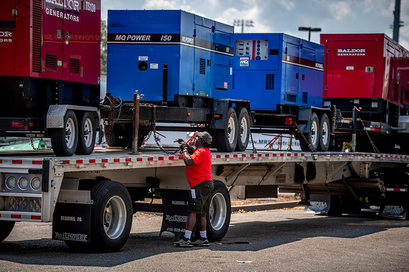 A worker unloads a truckload of generators delivered to the Claiborne Ave parking lot.