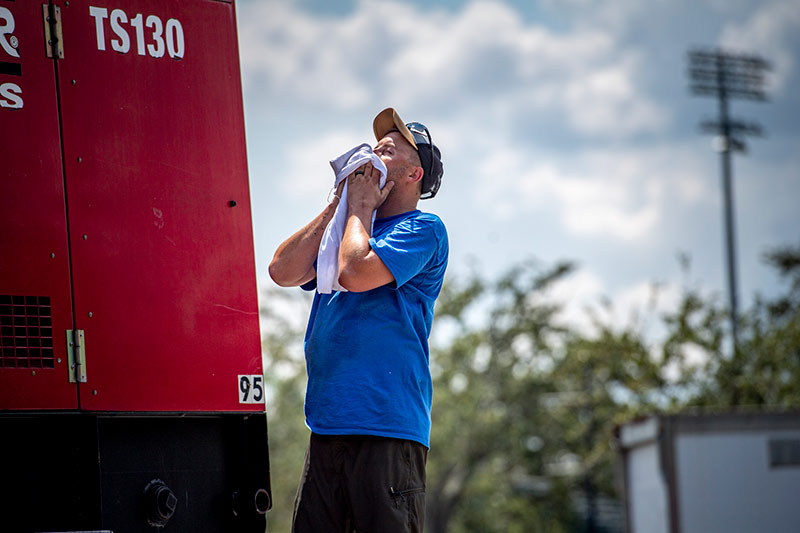 David Beauchamp with BMS CAT pauses to wipe sweat from his face as he unloads generators in the Claiborne Ave parking lot.