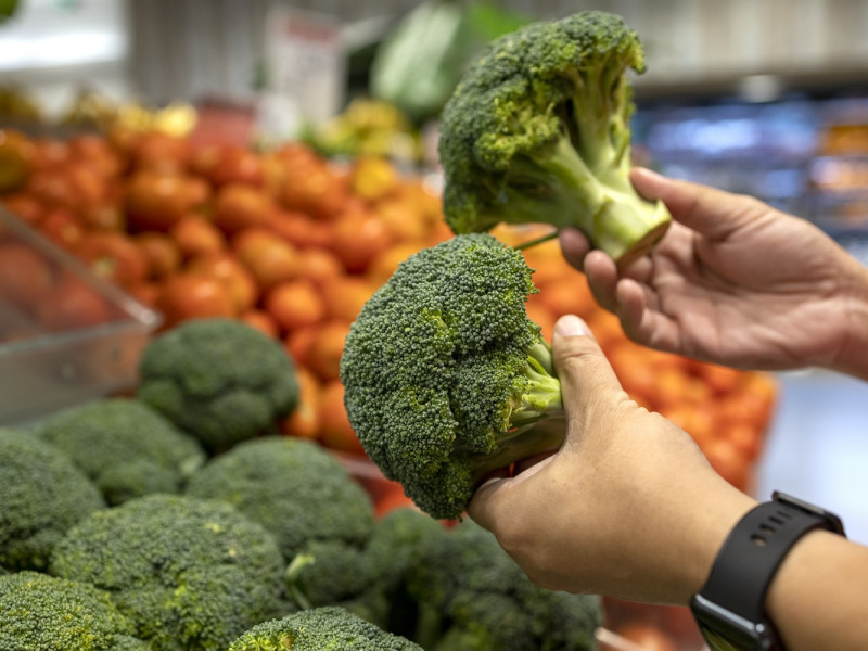 Man selects broccoli at store