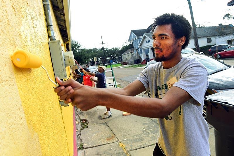 Tulane freshman Evan Doomes paints an exterior wall at Open Minds Open Hearts Daycare in New Orleans. Volunteers from local universities unite to honor Dr. Martin Luther King, Jr.