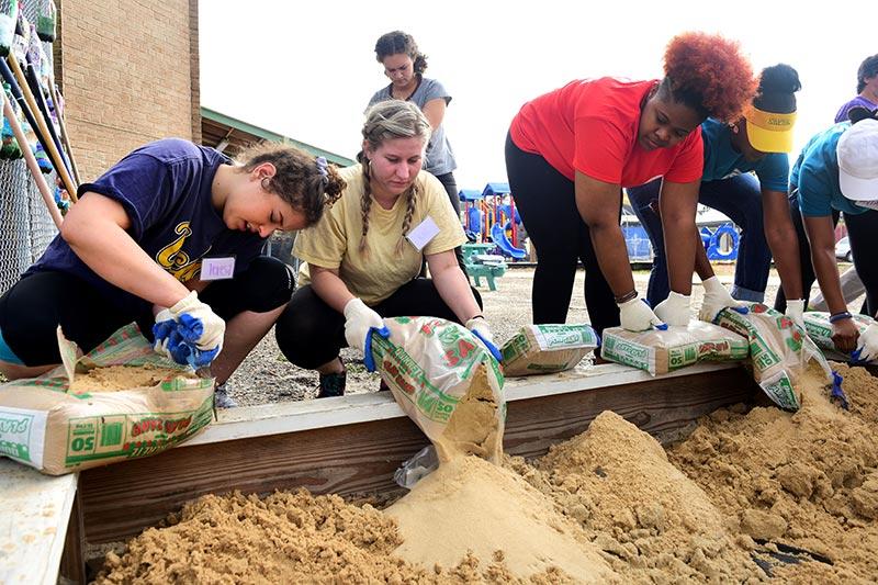 Tulane, Xavier and Loyola students work side-by-side to fill a sandbox at Homer Plessy School in the 7th ward. Volunteers from local universities unite to honor Dr. Martin Luther King, Jr.