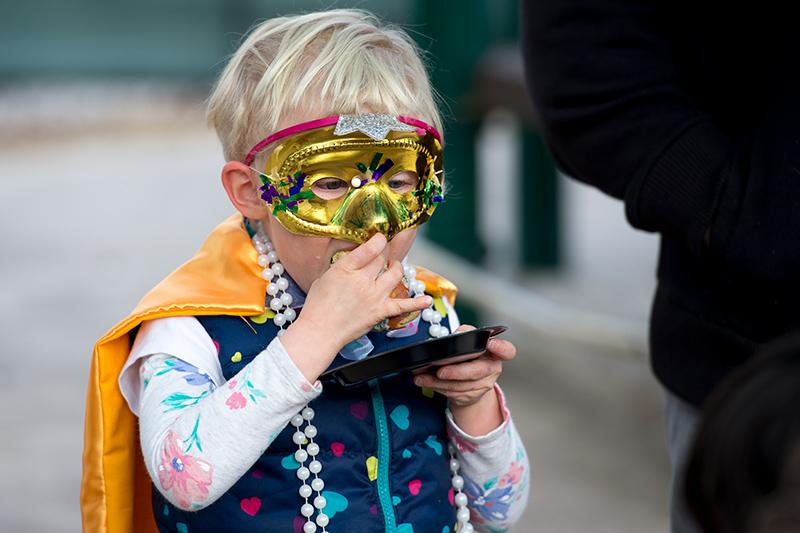 A young reveler savors a slice of king cake. Krewe of Newcomb rolls through the uptown campus spreading carnival cheer.