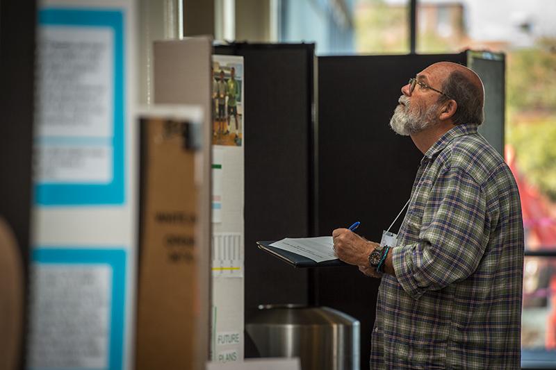 Will Knipmeyer, with the Mensa society, judges an entry in the competition. Young scientists converge on the uptown campus for annual science and engineering competition.