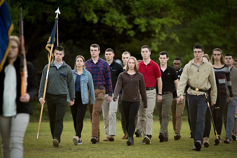 The battalion marches in formation to the beat of a bass drum. Navy ROTC students practice for annual promotion ceremony.