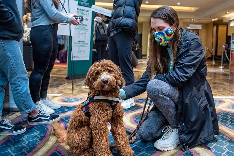 Casey, therapy dog in training, and Savanna Mayer check in at the Arrival Center. 