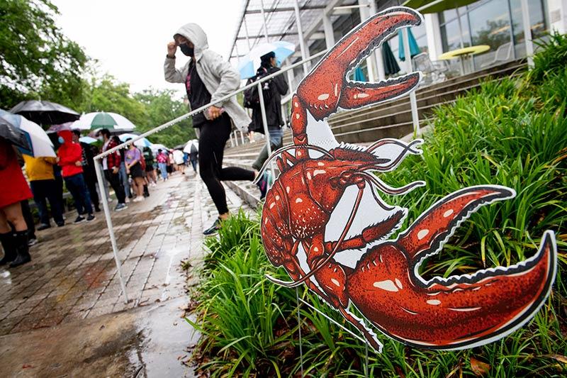 Members of the Tulane community wait in the rain outside the Tulane Dining Pavilion on the Berger Family Lawn.