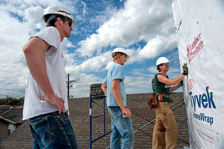 Ben Feiger, Mike Meline, and Kathleen Aurora Smith inspect the prep work before installing the siding.