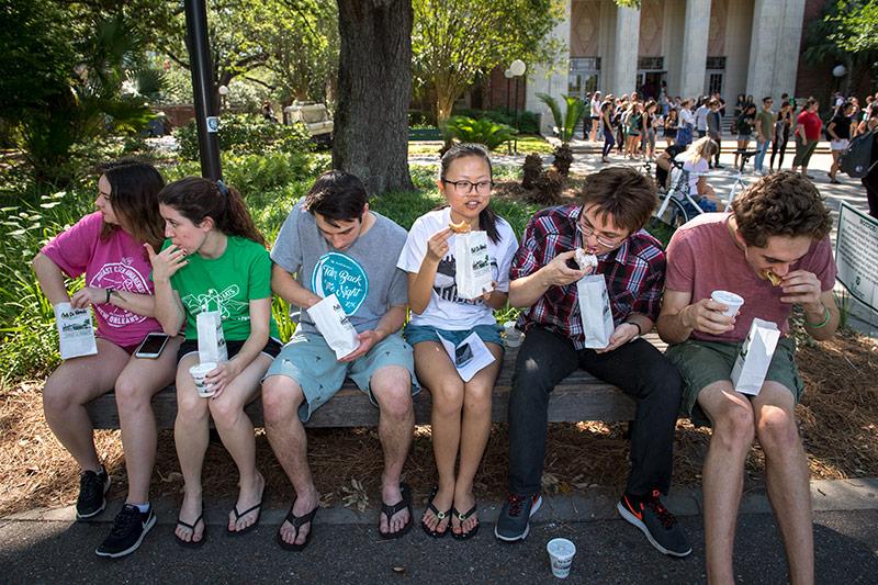 The joy of eating powdered fried dough is shared among friends, from left, Julia Ferro, Kameron Kane, Kyle Graesser, Stephanie Zhao, Marco Mirnics and Everest Shapiro. Local beignet vender drives onto campus to sweeten the semester’s end.